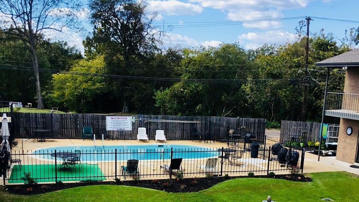 Pool and courtyard at Ellis Arms Apartments on a sunny day, with lounge chairs and the brick building beyond