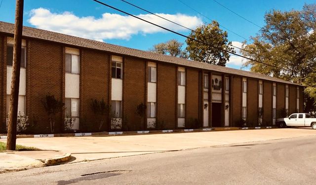 Wide street view of the long two-story brick Ellis Arms building under a blue sky