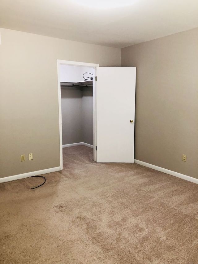 Bedroom in Unit 102 with the door open to a walk-in closet with shelving
