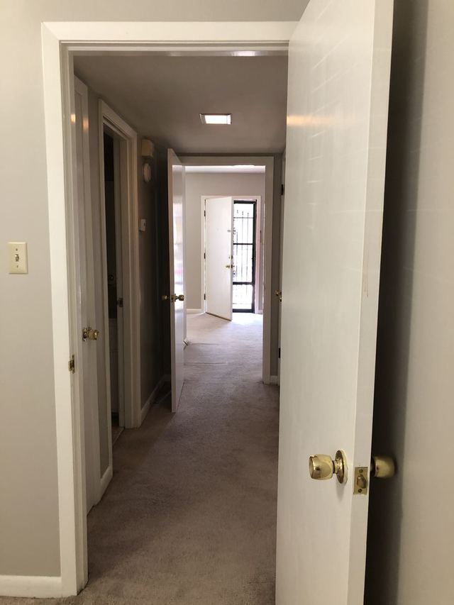 Carpeted hallway in Unit 102 looking toward the front door