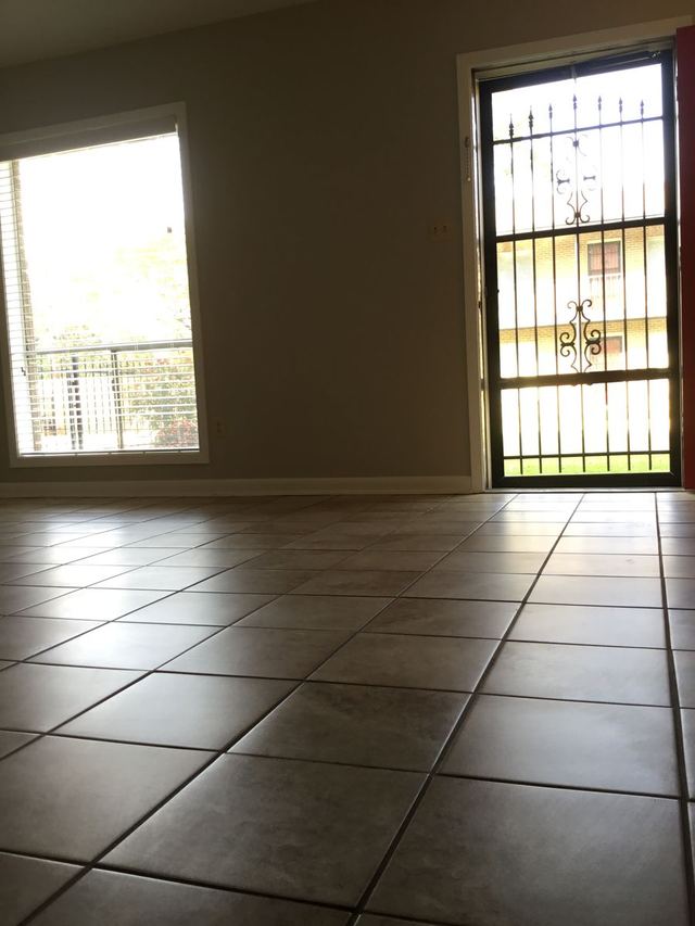 Living room in Unit 103 with tile flooring, light walls, and a large window