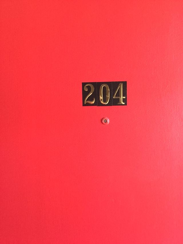 Red front door of Unit 204 with brass number plate