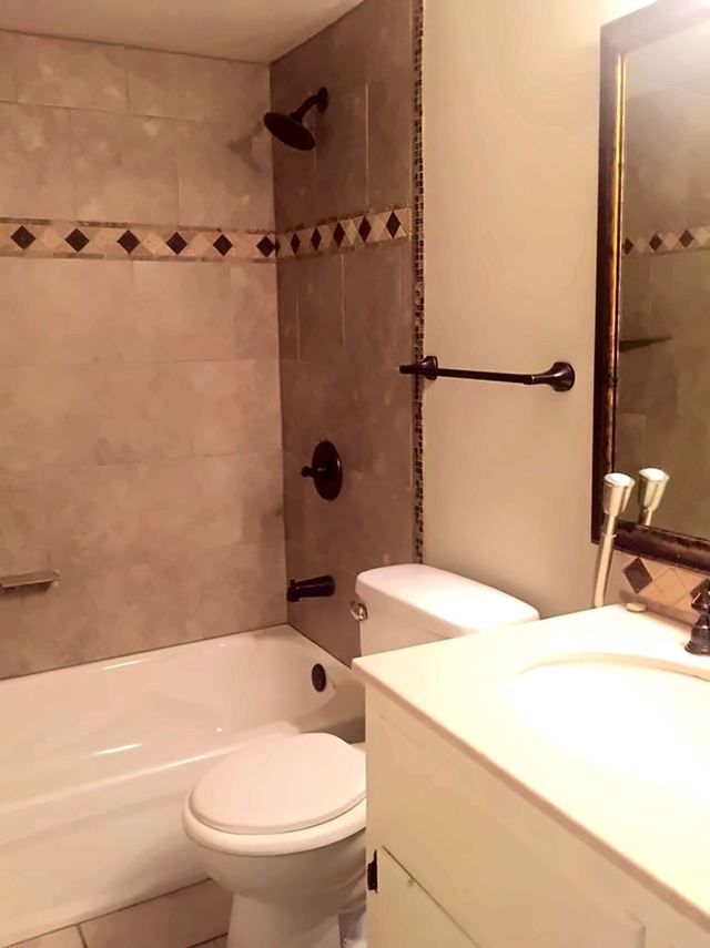Bathroom in Unit 206 with a tiled tub surround, dark fixtures, and a white vanity