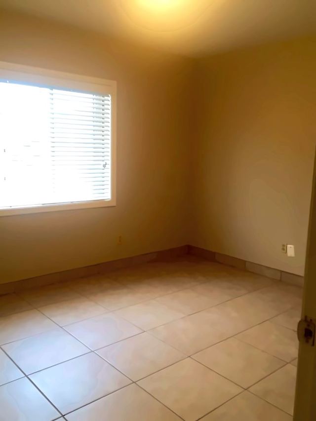 Bedroom in Unit 206 with light tile flooring and a window with blinds