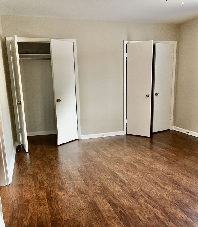 Bedroom in Unit 210 with dark wood-look flooring and two open closets