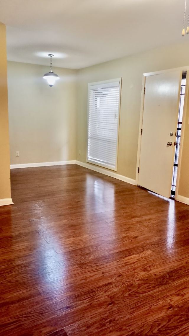 Living and dining area in Unit 210 with glossy dark wood-look flooring and a pendant light